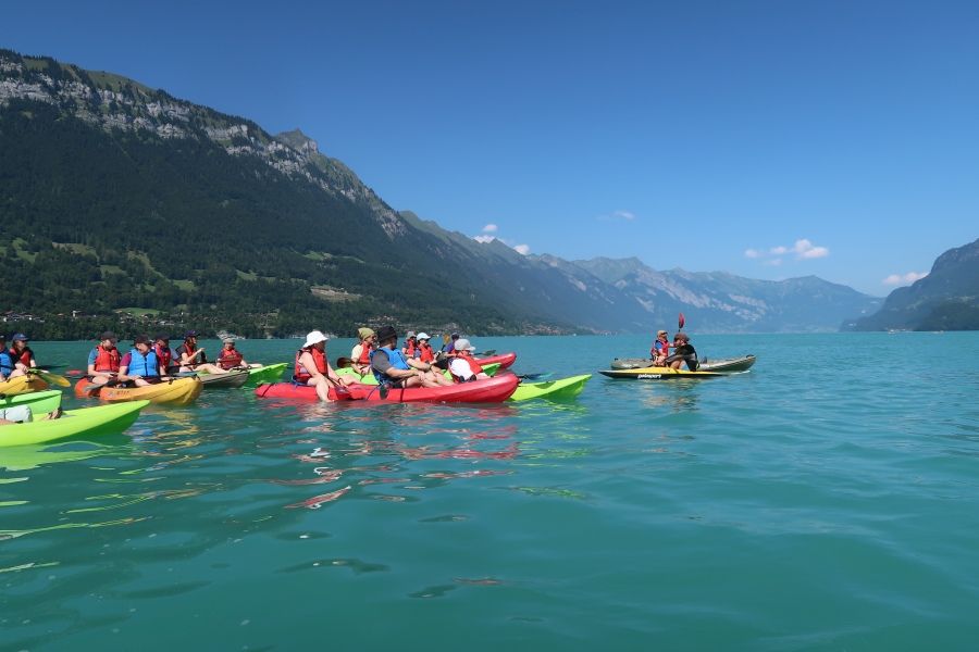 Gruppe von Kajak-Fahrer:innen auf dem Brienzersee vor Alpenkulisse